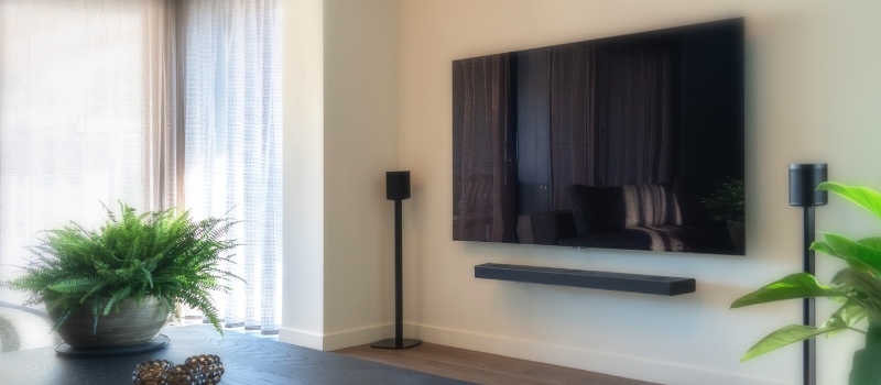 Determining the correct viewing height step by step Television with speakers on either side against a white wall in a bright living room.