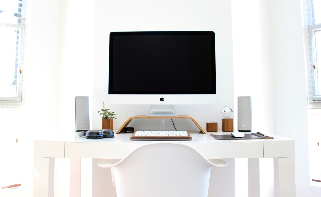 Minimalist desk with white speakers A modern white interior with a desk with a computer and two speakers on either side